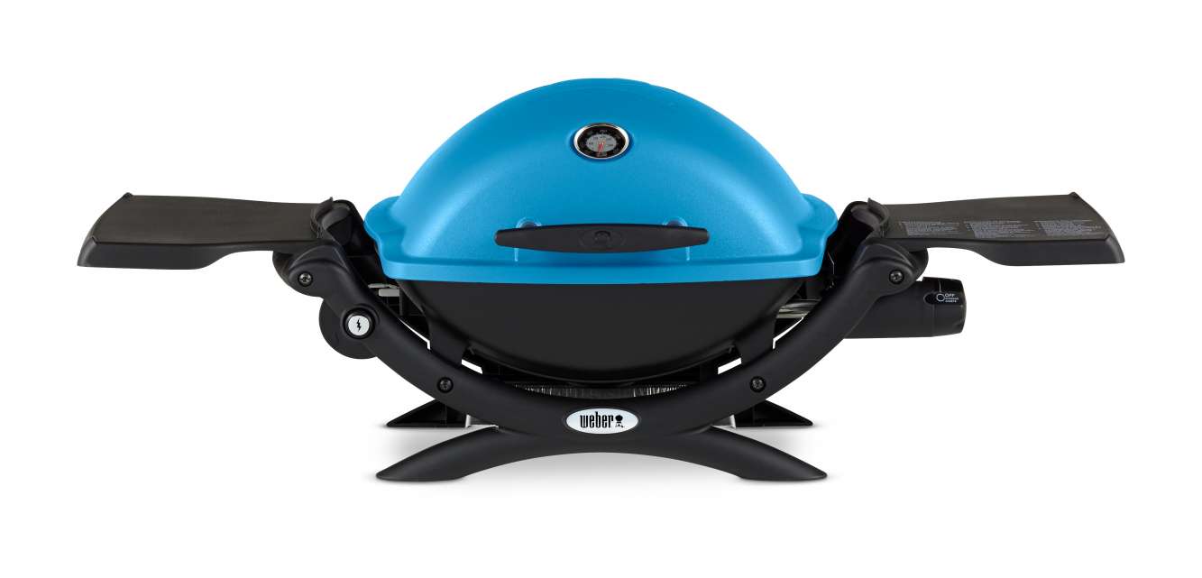 A bright blue portable Weber stove with a thermometer on the lid, featuring two black fold-out side tables and a sturdy black base, isolated on a white background.