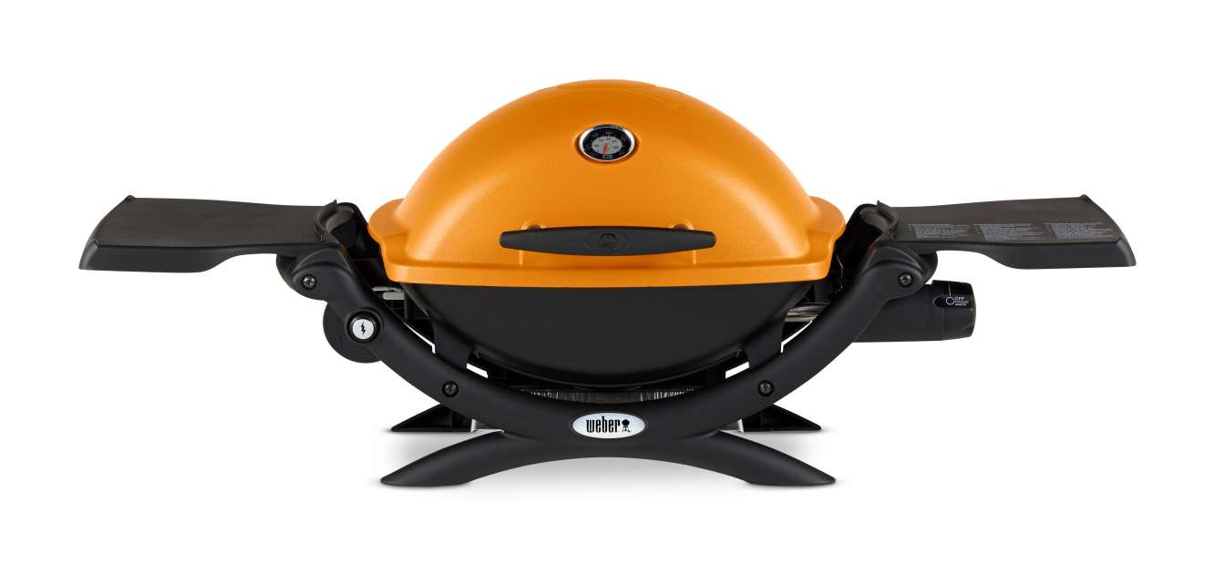 A portable Weber gas grill in orange, featuring a compact design with a rounded top, built-in temperature gauge, foldable side shelves, and a black base with an insert for a fire pit.