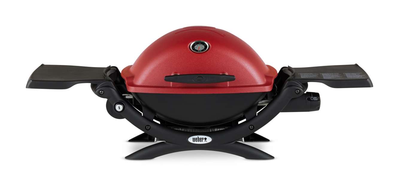 A red portable weber grill with a dome lid, featuring an integrated thermometer, mounted on a collapsible stand with side shelves and a fire pit insert.