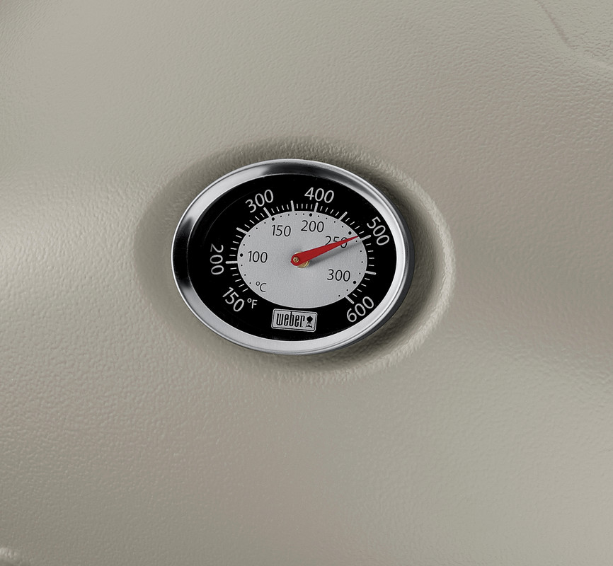 Close-up of a weber grill thermometer embedded in a gray stove surface, displaying a temperature around 200 degrees fahrenheit.