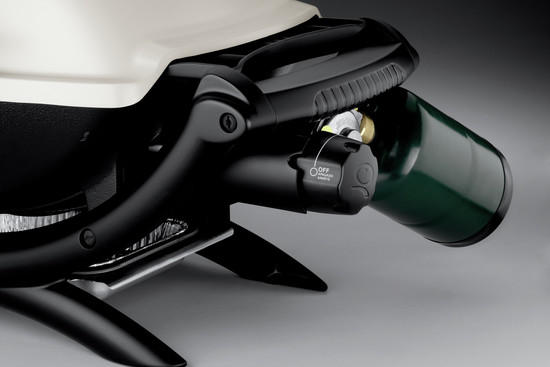 Close-up of a modern kitchen appliance, possibly a mixer, featuring a black control knob with on and off labels, and a lever positioned next to it. The device is mounted on a sleek gray base