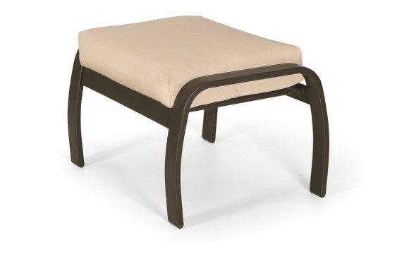A modern outdoor ottoman with a dark brown, metal frame and a light beige cushion near a fire pit on a white background.