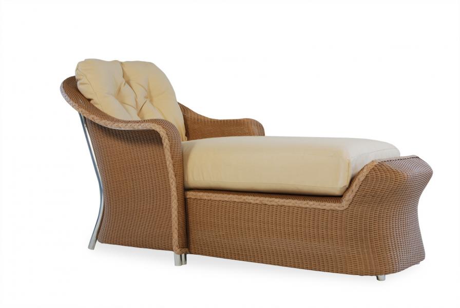 Elegant chaise lounge with a tufted backrest and a plush beige cushion, featuring a woven brown frame and stainless steel legs, isolated on a white background near an elegant fireplace.