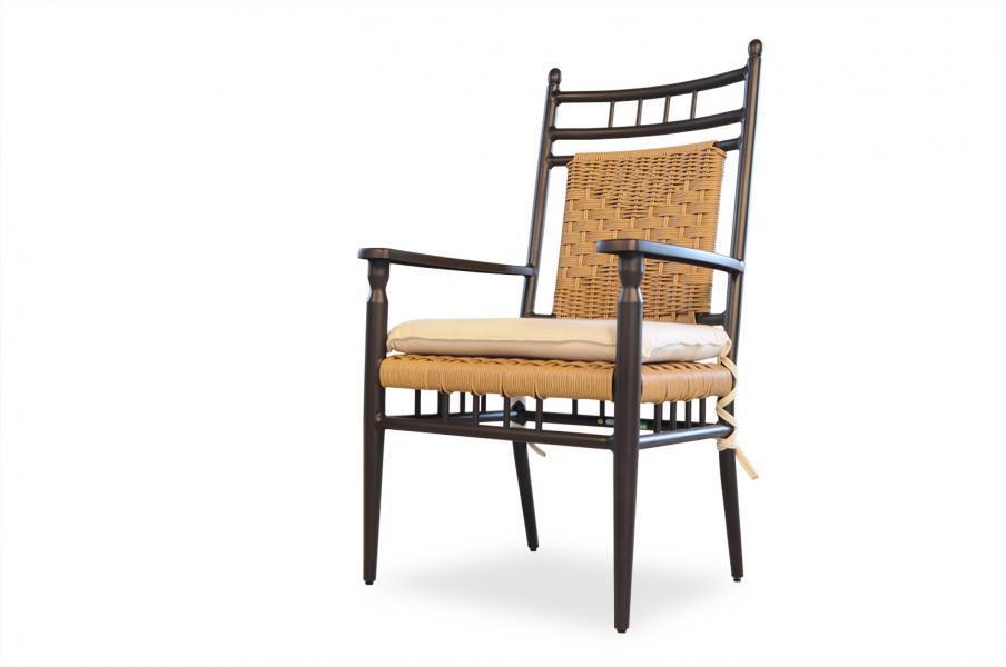 A wooden armchair with a rattan backrest and a cream cushion on the seat, isolated against a white background, ideal to complement a cozy fireplace setting.