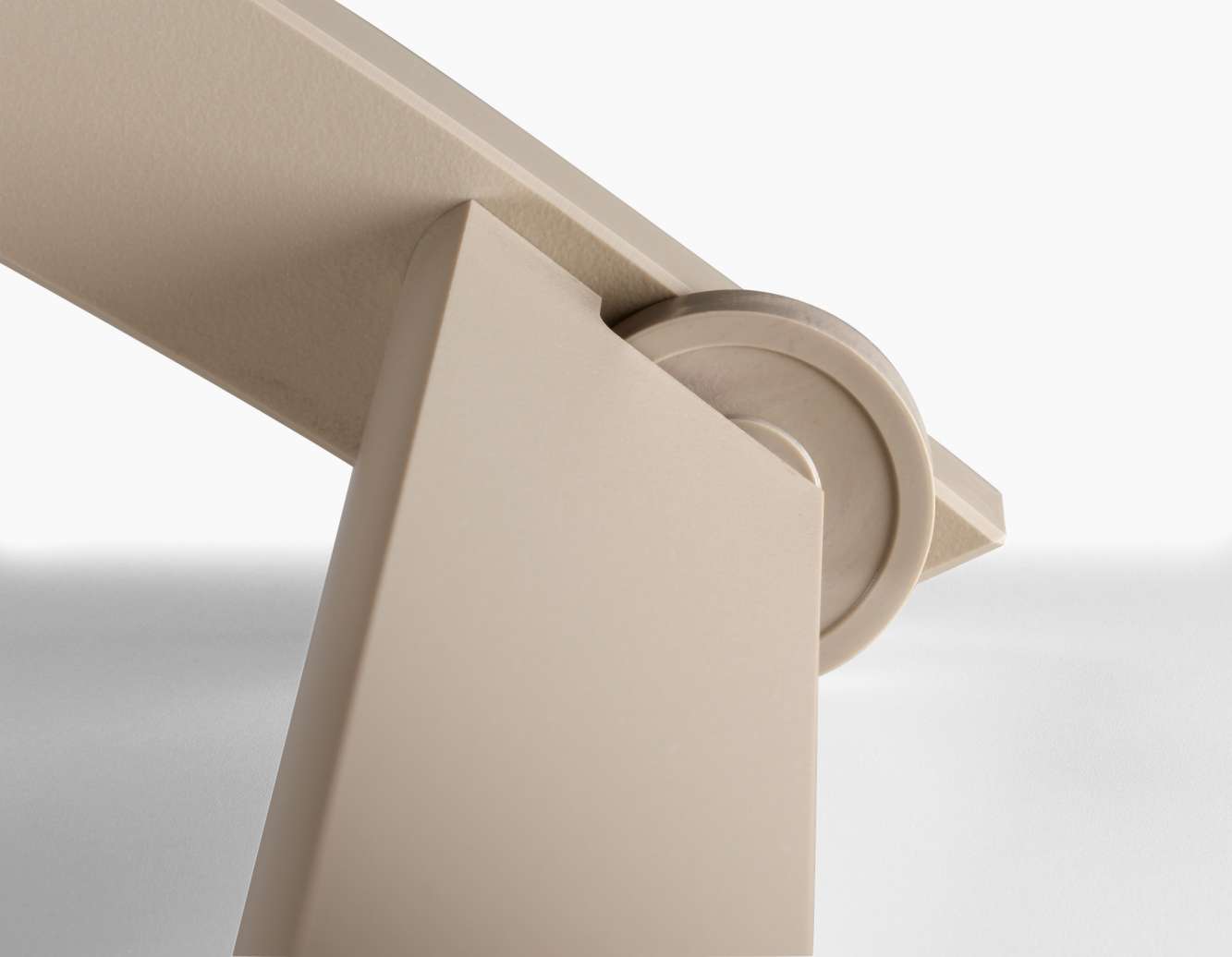Close-up view of a beige junction where two thin panels meet, supported by a cylindrical hinge, against a light background near a fireplace.