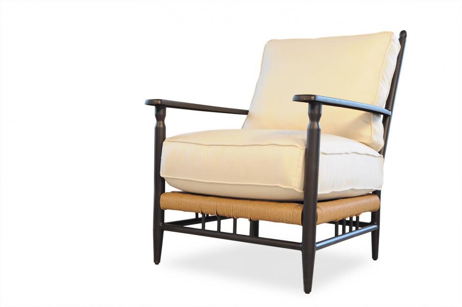 An elegant armchair with a cream cushion, dark wooden frame, and woven rattan accents, isolated on a white background near a fireplace.
