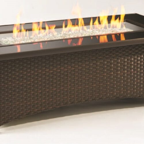 Rectangular fire pit table with a woven base and a glass frame around the flames, showcasing a modern design. Flames are visible over a bed of clear glass rocks.