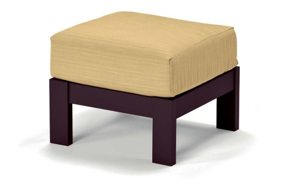 A contemporary ottoman with a beige cushion on top of a dark mahogany wooden base, isolated against a white background with a fireplace insert visible in the setting.
