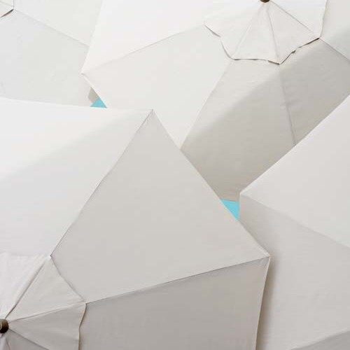 Overhead view of multiple open white umbrellas arranged closely together, with portions of a teal background peeking through near a stove.