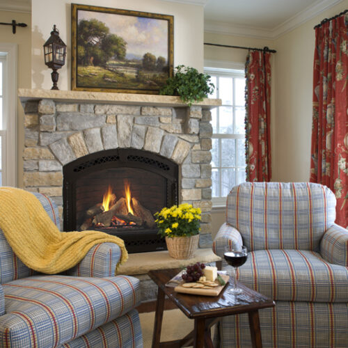 Cerona gas fireplace by Heat & Glo in black against a tan stone masonry hearth in a living room
