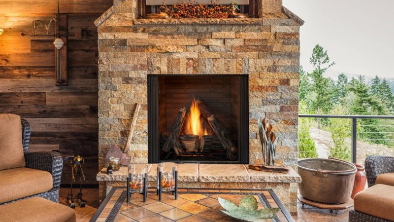 Courtyard outdoor gas fireplace by Outdoor Lifestyles against a tan stone masonry hearth in an outdoor living space