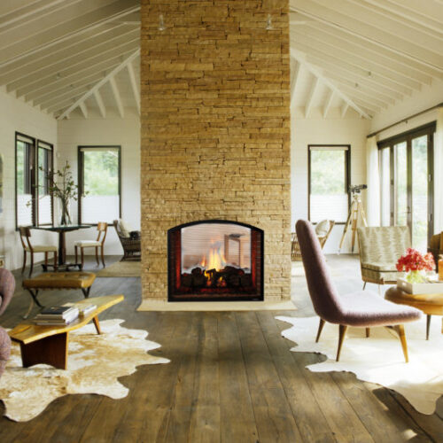 Escape ST see-through gas fireplace by Heat & Glo in black with Arched Firescreen front against tan stone masonry