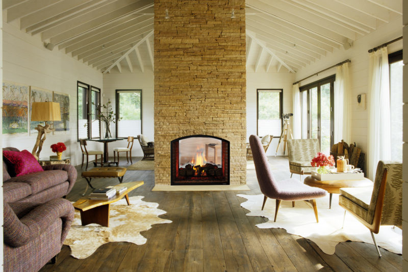 Escape ST see-through gas fireplace by Heat & Glo in black with Arched Firescreen front against tan stone masonry