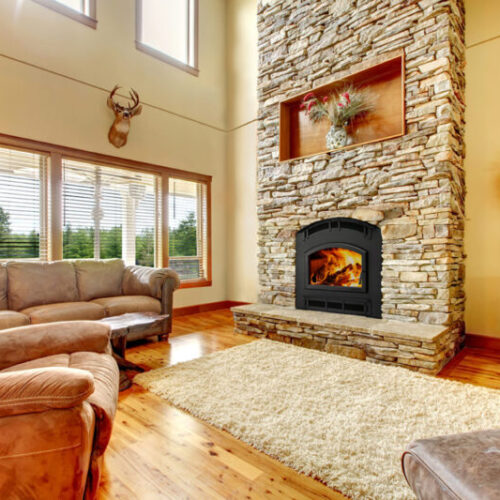 Pioneer III wood fireplace by Quadra-Fire in Classic Black with black arched door against tan stone masonry