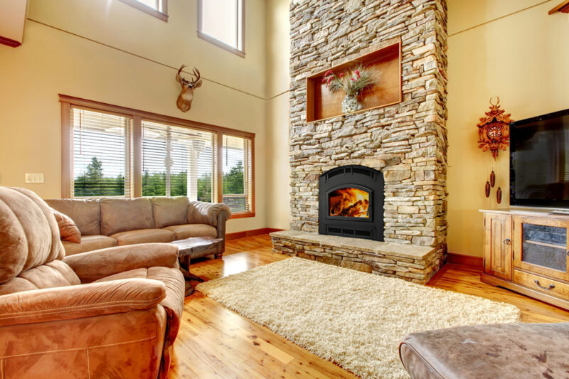 Pioneer III wood fireplace by Quadra-Fire in Classic Black with black arched door against tan stone masonry