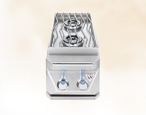 A commercial stainless steel double-basket deep fryer with two temperature control knobs and a stove insert, viewed from a frontal angle on a light beige background.