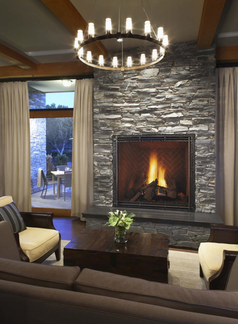 TRUE 42 inch gas fireplace by Heat & Glo in black with Forge front against a gray stone masonry hearth
