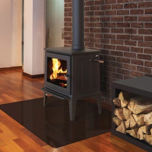 A modern wood-burning stove with visible flames is set against a brick wall in a cozy room. a wood storage box sits nearby on a polished wooden floor.
