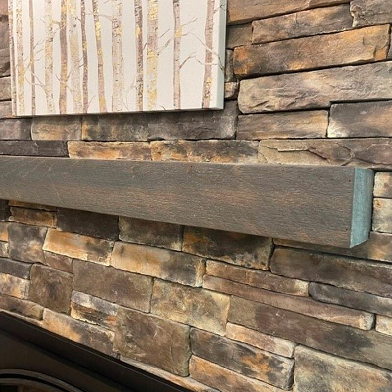 A rustic stone fireplace featuring a dark wooden mantel and a decorative painting of birch trees hanging above it.