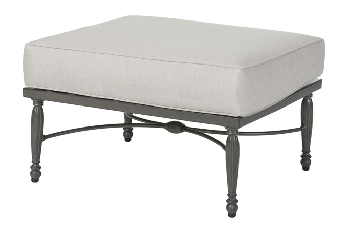 A rectangular ottoman with a gray cushioned top and a decorative, dark metal frame featuring intricate Gensun Bel Air scroll detailing.
