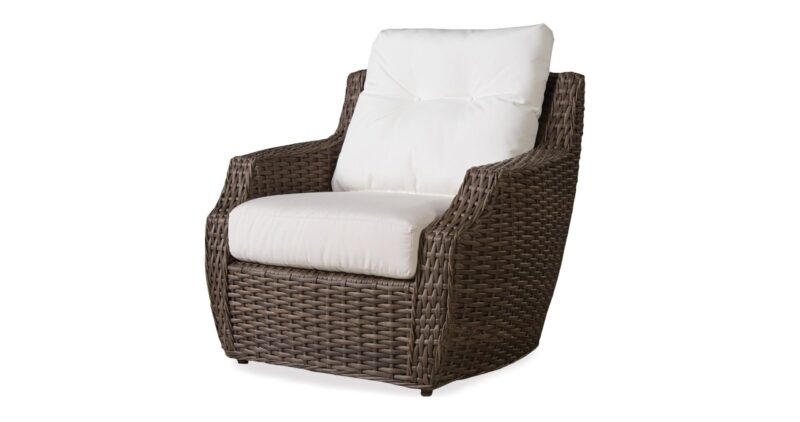 An elegant wicker armchair with plush white cushions, isolated on a white background.