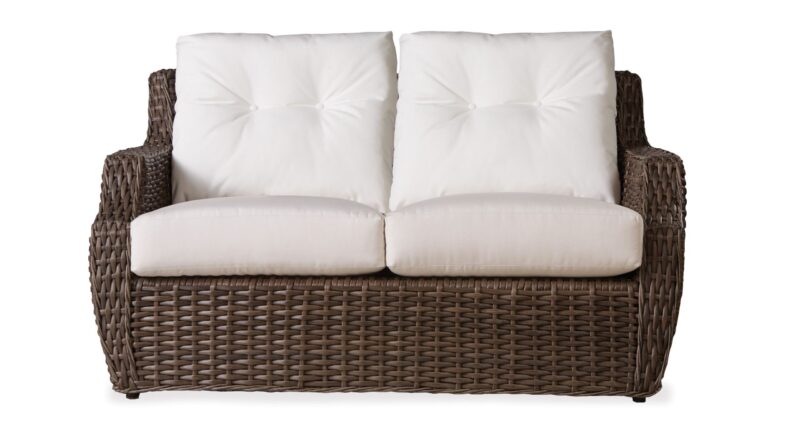 Two-seater wicker sofa with plush white cushions, isolated on a white background.