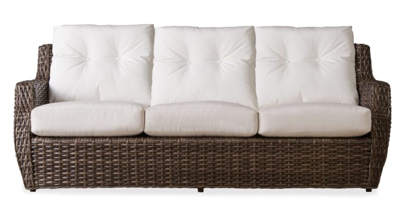 Wicker three-seater couch with plush white cushions on a seamless white background.