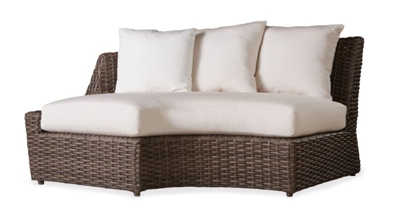 Outdoor rattan loveseat with a large seat cushion and several plush back pillows, set against a plain white background.