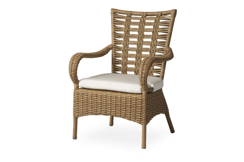 A high-back wicker chair with armrests and a white cushion on a white background.