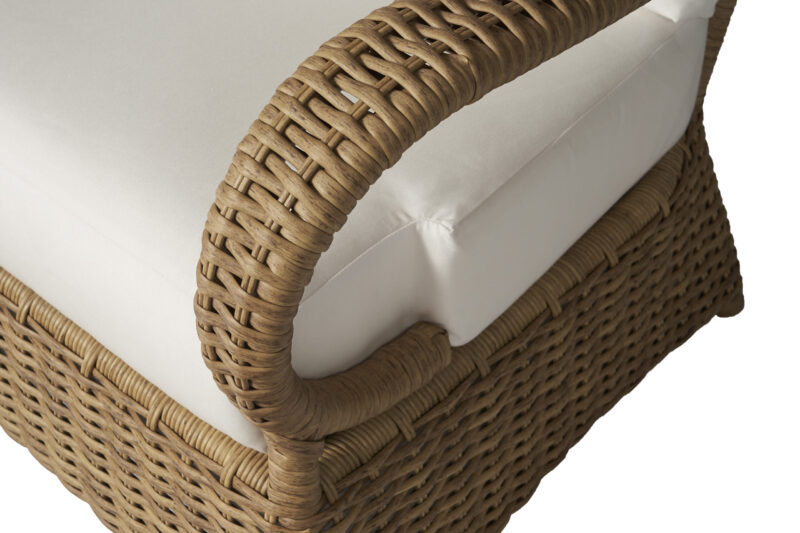 Close-up of a beige cushion on a wicker chair showcasing intricate weaving details on the arm of the chair. the focus is on the texture and craftsmanship.