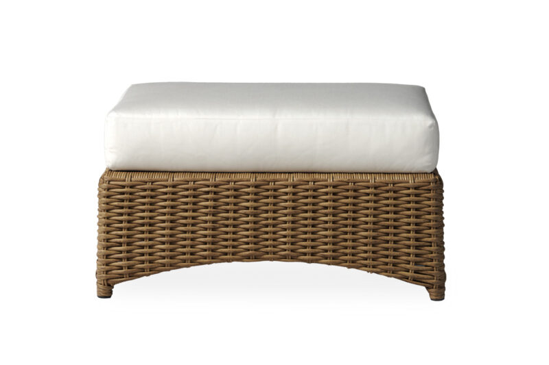 A wicker ottoman with a curved base and a thick, white cushion on top, isolated on a white background.