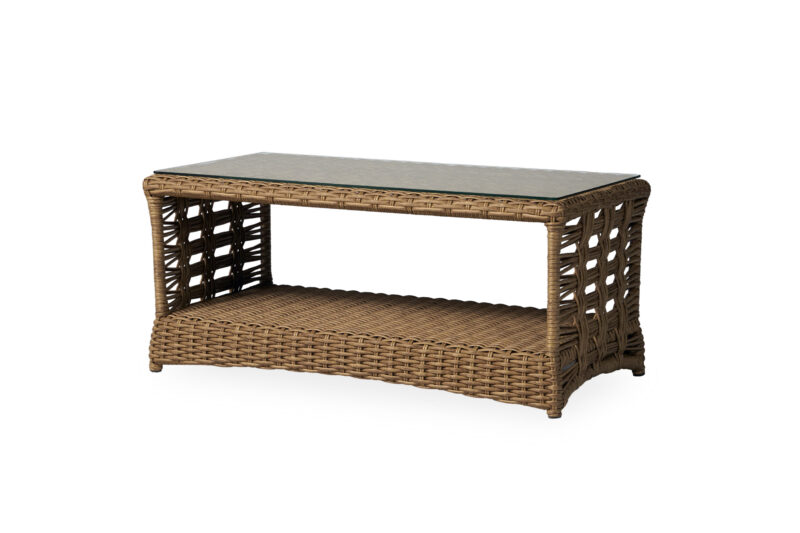 A wicker coffee table with a rectangular structure and a glass top, featuring an open shelf below. the table is set against a plain white background.