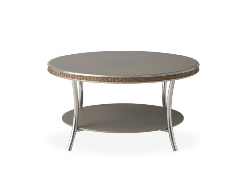 A modern round coffee table with a light gray tabletop and a rattan edge, featuring a secondary shelf below. the table is set against a white background.