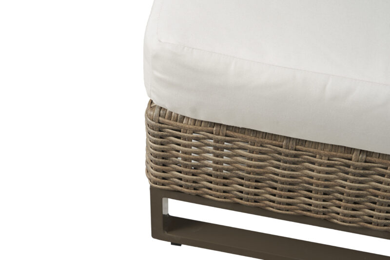 Close-up of a modern outdoor ottoman with a white cushion on top of a woven wicker base and a metal frame, isolated on a white background.