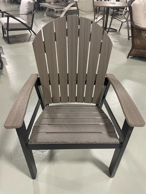 A close-up of a modern Newport Adirondack chair with a grey slatted back and seat, contrasted by black arms and legs, displayed in a store with other furniture in the background.