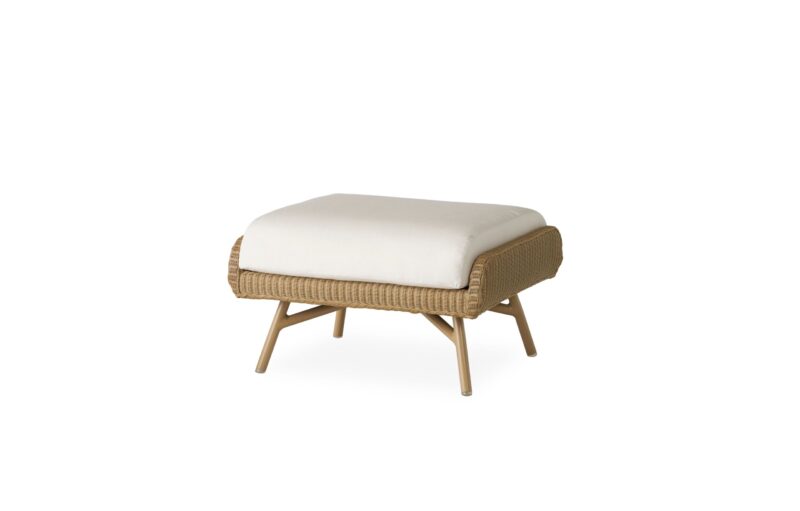 A modern ottoman with a beige cushion on a woven wicker base and wooden legs, isolated on a white background.
