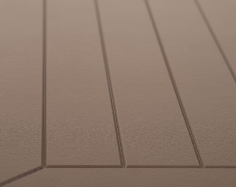 Close-up of a beige surface with geometric lines and shadows creating a pattern of rectangles and trapezoids, showing depth and texture.