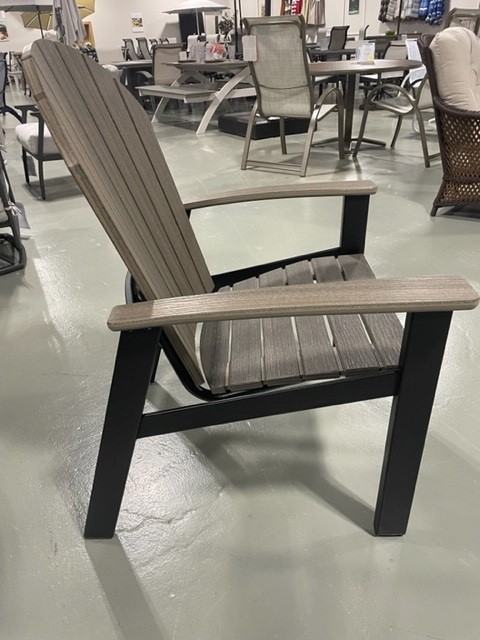 A modern Newport Adirondack chair with a black frame and gray slatted seat and backrest, displayed on a concrete floor in a furniture showroom with various other furniture items in the background.