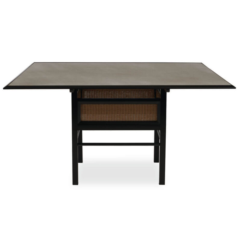 A square, dark-colored dining table with an extendable feature and a lower shelf that holds a rattan basket, set against a plain white background.