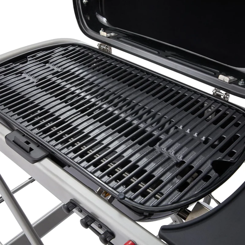 Close-up of a clean, black grill grate on a Weber Traveler gas barbecue with the lid open, displaying the cooking surface and part of the exterior body.