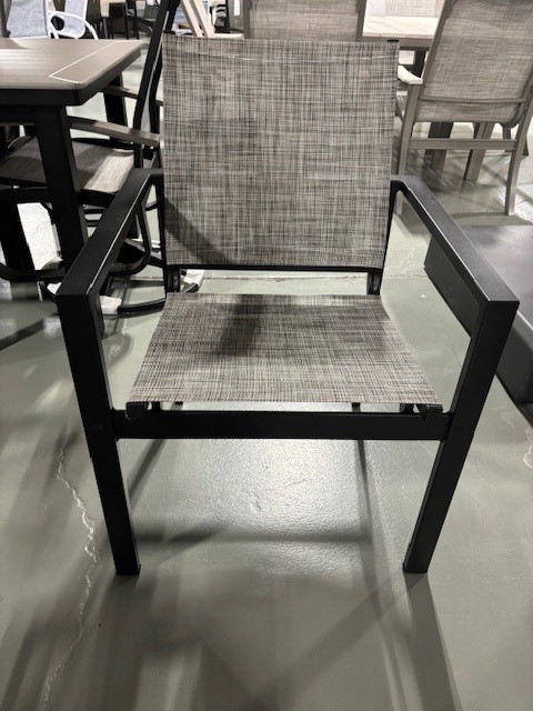 A modern gray woven outdoor chair with a black metal frame, displayed on a glossy concrete floor in a Tribeca showroom.