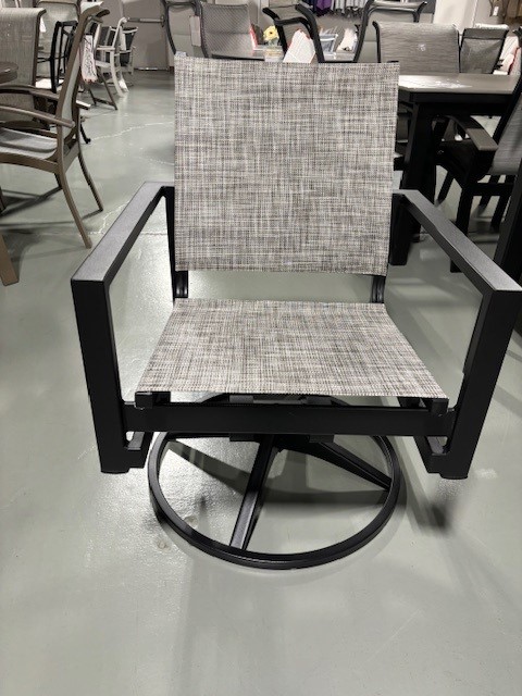 A modern swivel chair featuring a black frame and Tribeca plaid upholstery, displayed in a furniture showroom with other chairs visible in the background.