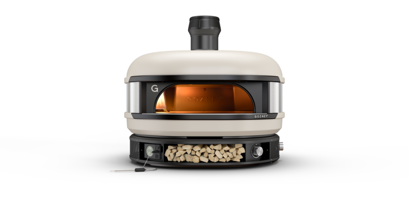 A modern, portable pizza oven with a metal body and visible fire chamber, branded "gozney." the oven has a stone baking floor and a chimney, set against a plain white background.