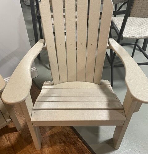 A beige adirondack chair made of plastic, positioned in an indoor Harbor View space with metal tables and chairs in the background.