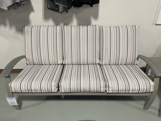 A modern outdoor sofa with a striped cushion on a metal frame, displayed in a store setting.