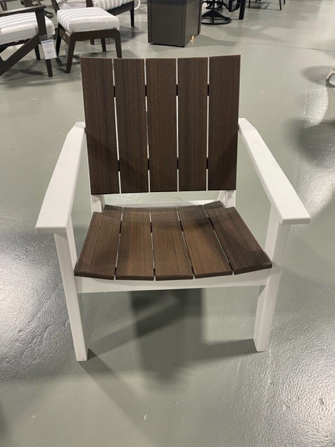 A modern chair with a white frame and dark brown wooden slats on the seat and backrest, displayed in a furniture store.