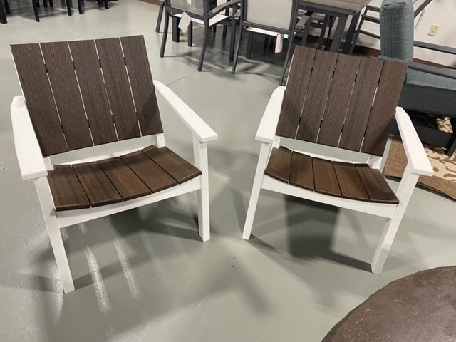 Two adirondack chairs with white frames and brown slatted seats and backs, positioned on a gray floor in an indoor setting.