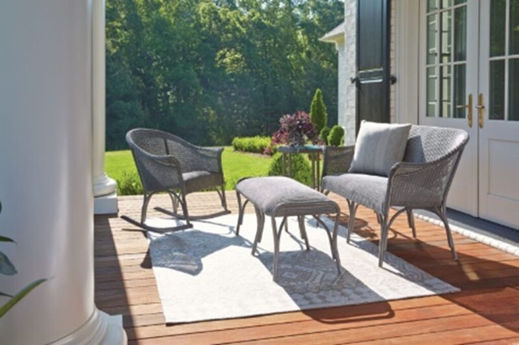 pewter-colored Lloyd Flanders all-weather wicker lounge set on a wood plank porch, neutral rug on wood plank porch