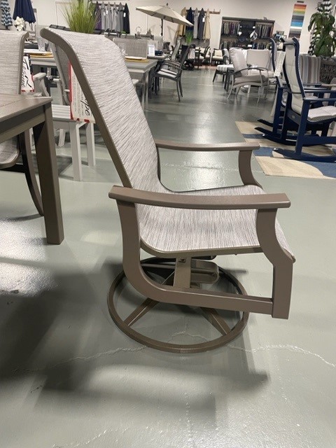A modern St. Catherine Sling rocking chair made of gray and brown materials with a woven backrest and seat, displayed in a furniture store.