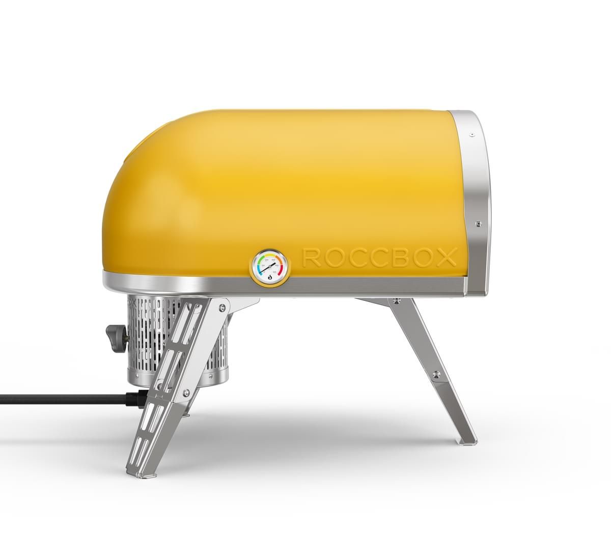 A limited edition yellow Roccbox portable pizza oven with silver legs and trim, isolated on a white background.